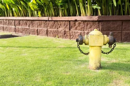 Finished concrete block retaining wall bordering a level lawn in Central New Jersey