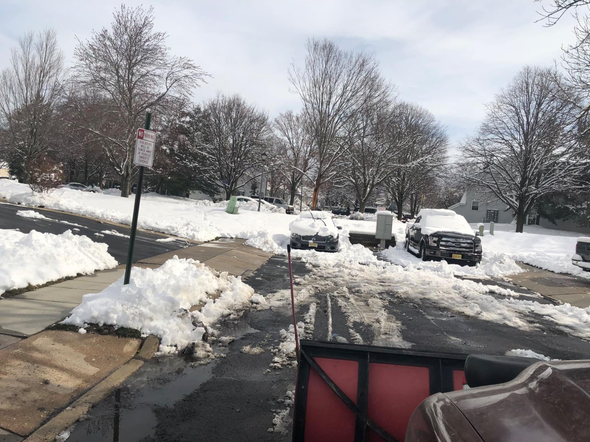 Plow truck clearing a snow-covered residential driveway in a New Jersey neighborhood
